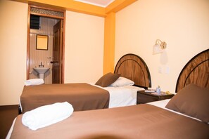 A hotel room with two beds, a bathroom with a sink, and a mirror. - Samary Hostel (Puno)