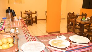 A dining area with tables set for a meal, including plates of food, a thermos, and a bowl of lemons. - Samary Hostel (Puno)