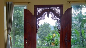 A wooden door with intricate carvings, leading to a garden view. - Atres Sari Resort (Munduk)