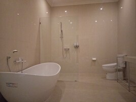 Un baño moderno con una bañera independiente, ducha con mampara de vidrio y un inodoro.