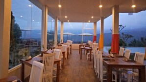 A restaurant with a view of mountains, large windows, and outdoor umbrellas. - Atres Sari Resort (Munduk)