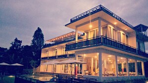 A multi-story building with balconies, large windows, and outdoor seating areas. - Atres Sari Resort (Munduk)