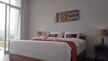 Ein Schlafzimmer mit einem großen Bett, Blick durch das Fenster und einem an der Wand befestigten Kunstwerk.