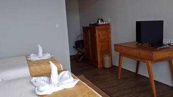 Una habitación de hotel con una cama, un escritorio con televisor y un armario de madera.