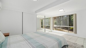 A bedroom with a large bed, a sliding door closet, and a view of the outdoors through a window with a mesh screen. - Serene Family Escape with Pool (WOORIM)