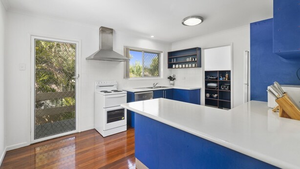 A modern kitchen with white and blue cabinetry, a stainless steel range hood, and a large island with a knife block. - Serene Family Escape with Pool (WOORIM)