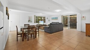 A spacious living area with a dining table, chairs, a gray sofa, and a TV. - Serene Family Escape with Pool (WOORIM)