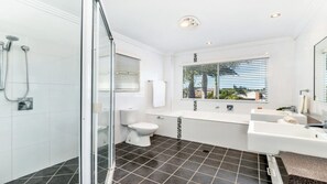 A modern bathroom with a glass shower enclosure, a toilet, a bathtub, and a sink.