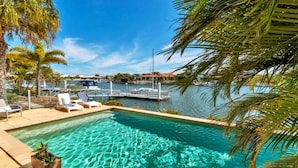 A clear pool with a view of a marina and boats.