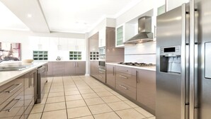 A modern kitchen with stainless steel appliances, white cabinetry, and a tiled floor.