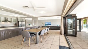 A modern kitchen with a central island, a dining area with a wooden table and chairs, and a large sliding glass door leading to an outdoor area.