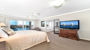 A hotel room with a large bed, a television, and a view of the sea.