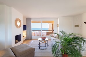 Un salón moderno con balcón, un espejo redondo, una mesita, un sofá y una planta en maceta.