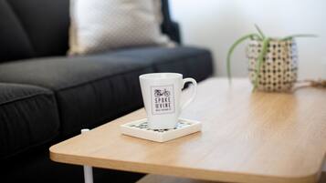 Une tasse blanche ornée d’un logo de vélo, posée sur un dessous de verre, sur une table en bois.