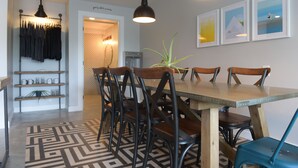 A dining area with a wooden table and chairs, a patterned rug, and pendant lighting. - Spoke and Vine Motel (Palisade)