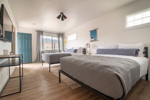 Un dormitorio con dos camas, un escritorio, un televisor y una ventana.