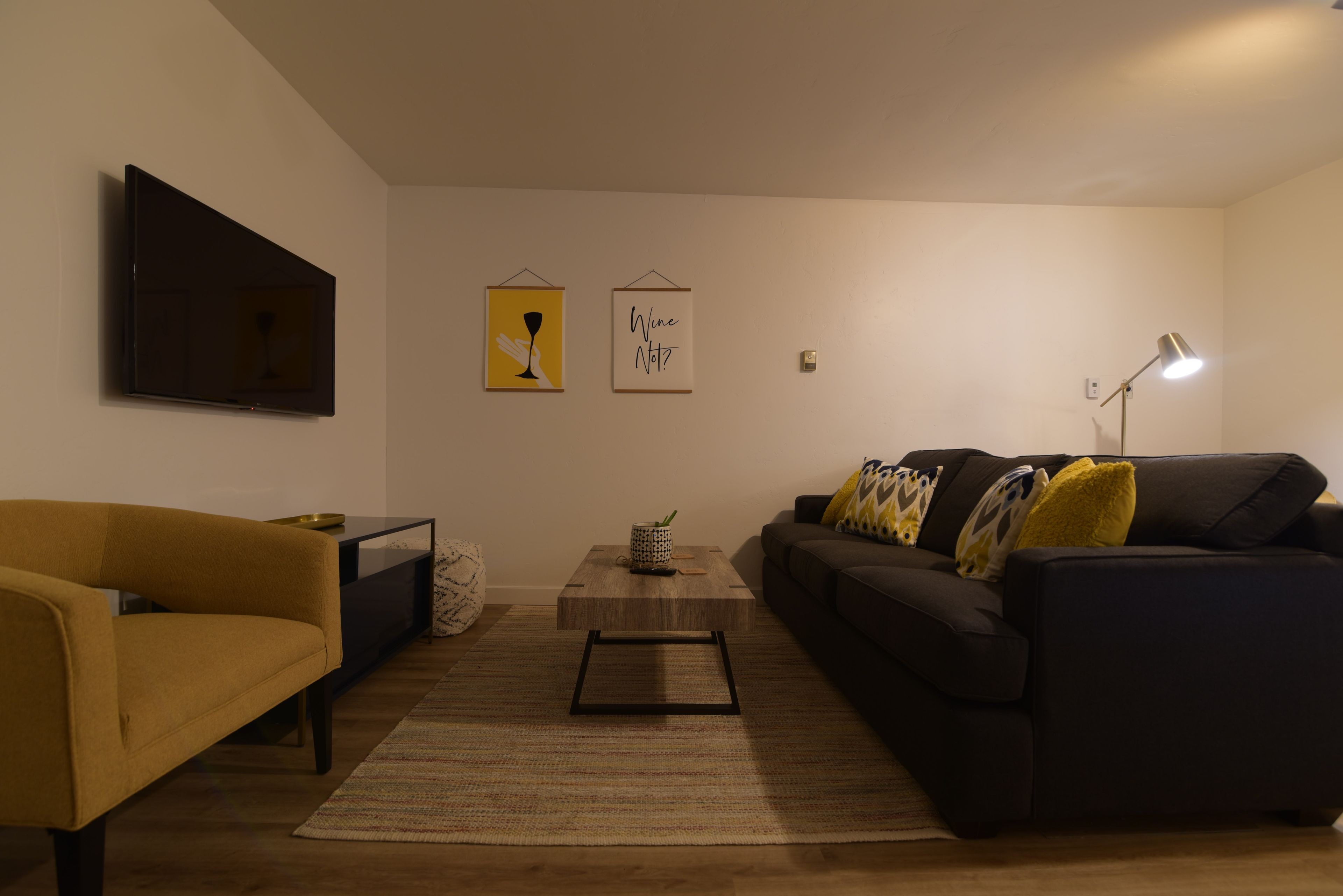 A living room with a sofa, a coffee table, and a TV mounted on the wall.
