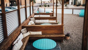 A covered outdoor seating area with wooden benches and a round table. - Spoke and Vine Motel (Palisade)