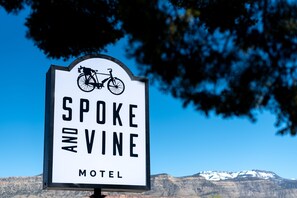 A sign for the Spoke and Vine Motel with a bicycle symbol, set against a mountainous backdrop. - Spoke and Vine Motel (Palisade)