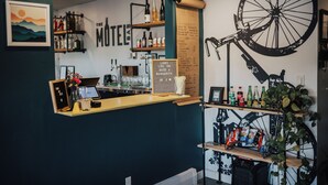 A bar area with a bicycle wheel decoration, a bar menu, and shelves with bottles and snacks. - Spoke and Vine Motel (Palisade)