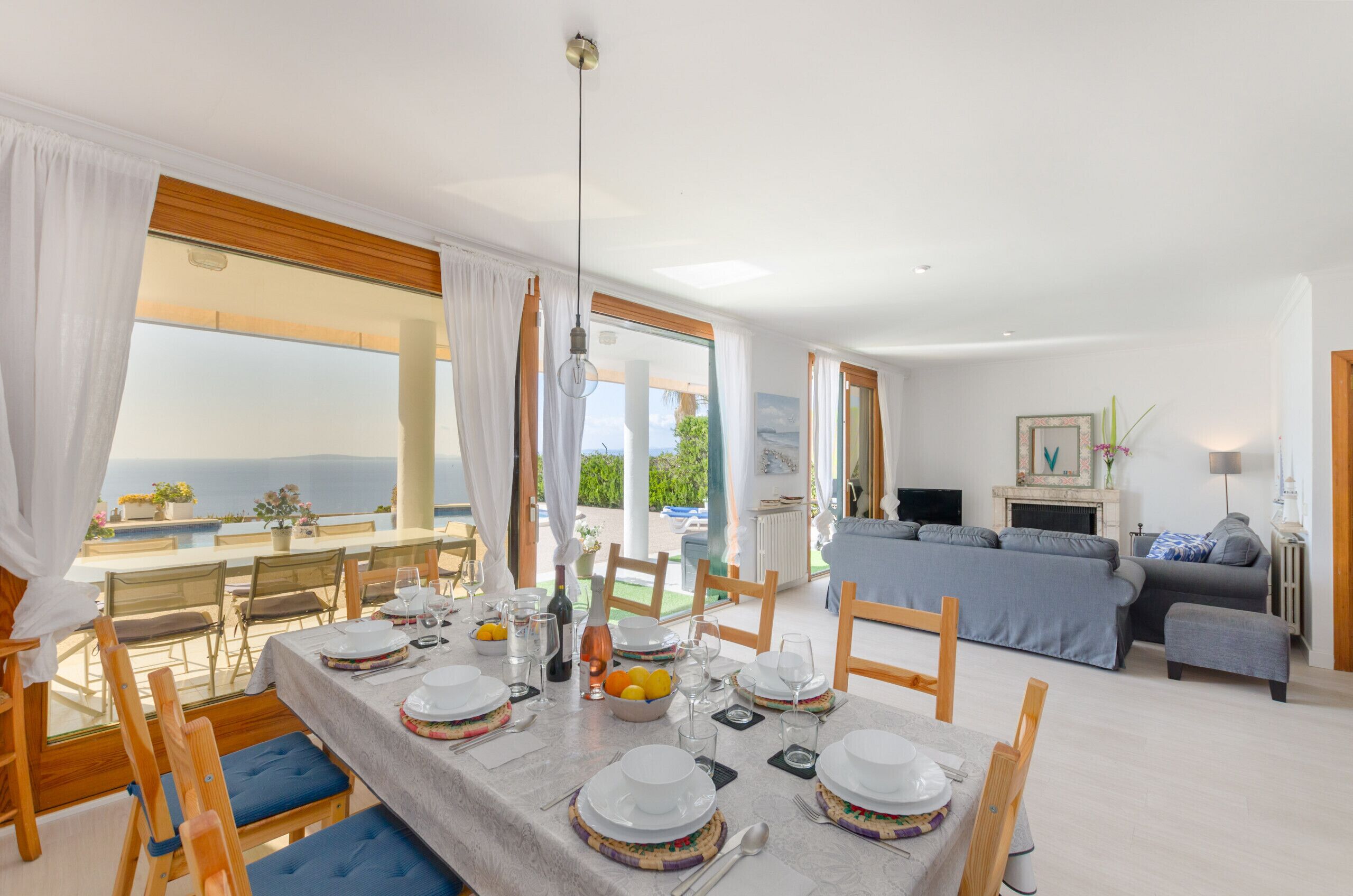 A dining area with a table set for four, a sofa, and a view of the sea.