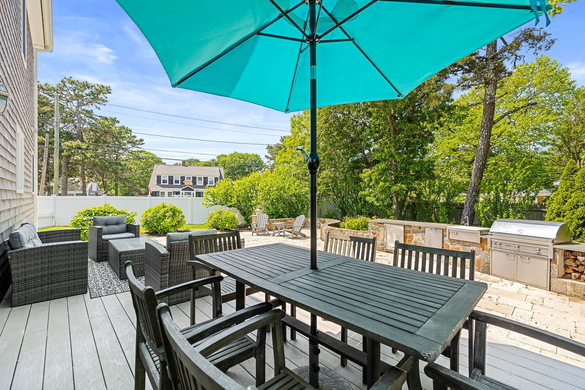 An outdoor patio with a table and chairs, a grill, and a large umbrella.