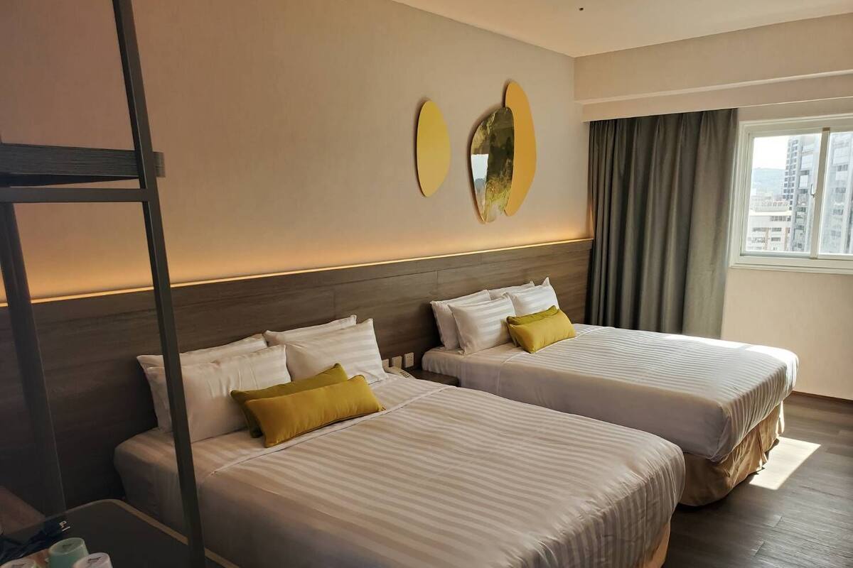 A hotel room with two beds, a nightstand, and a window with curtains.
