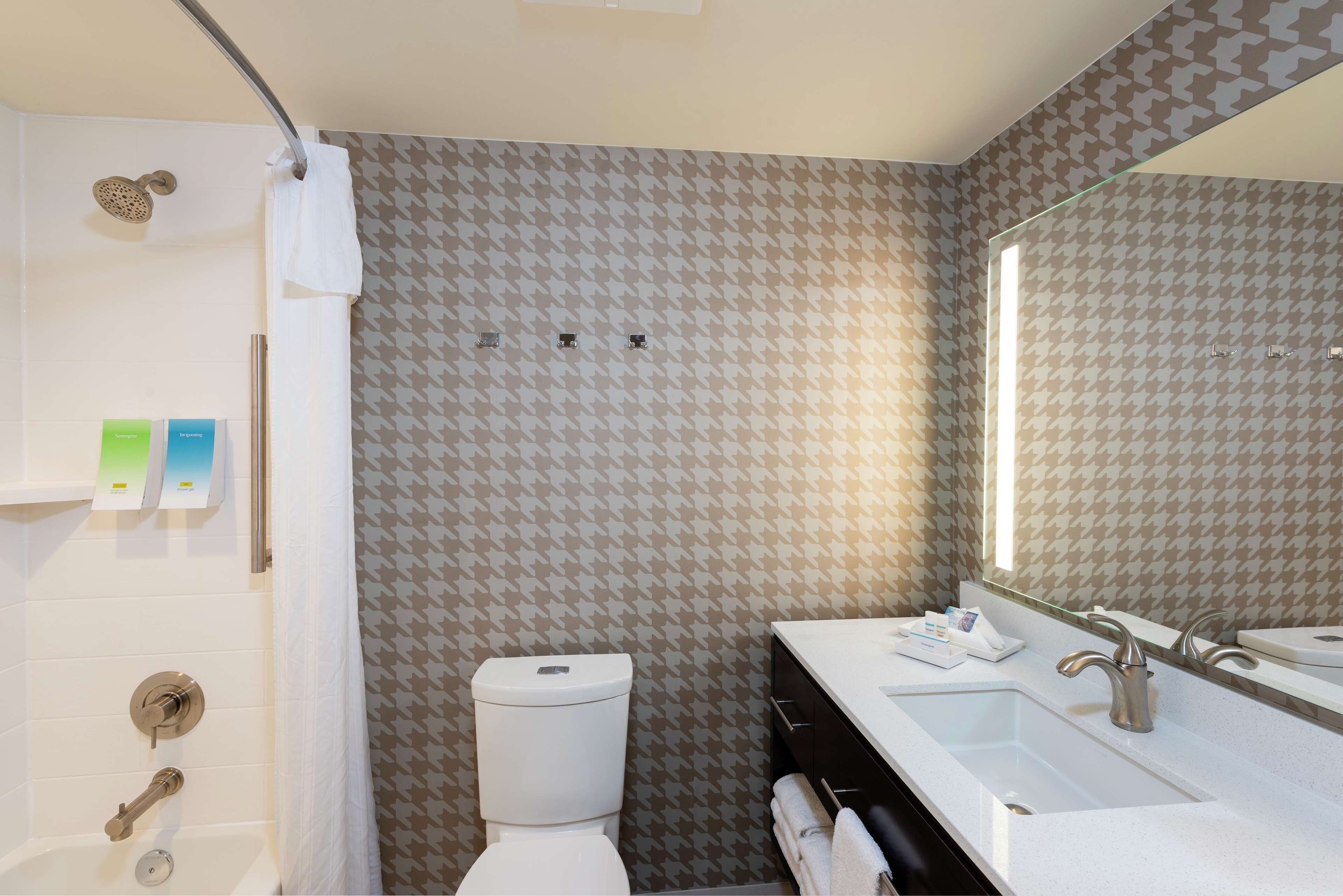 A modern bathroom with a shower, toilet, and sink.
