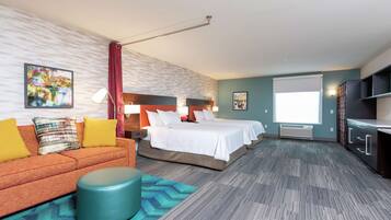 Quarto de hotel com duas camas, um sofá, uma televisão e uma janela grande.