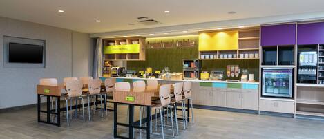 A modern restaurant with a long counter, multiple chairs, and a variety of food items on display.