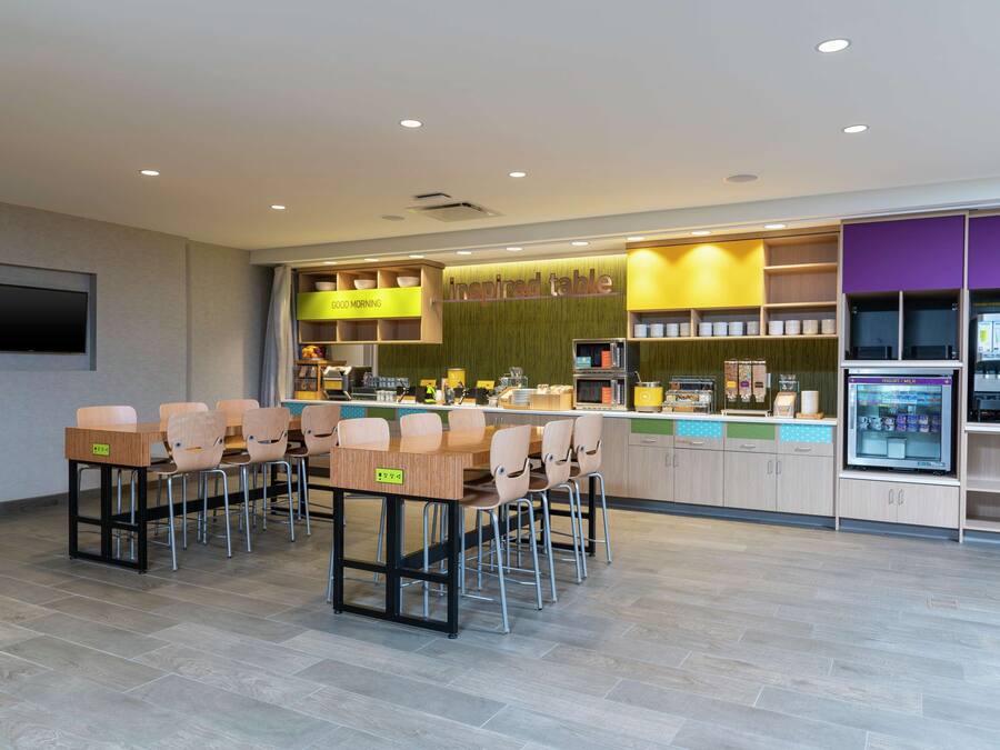 Un restaurante moderno con una barra larga, numerosas sillas y una variedad de alimentos a la vista.