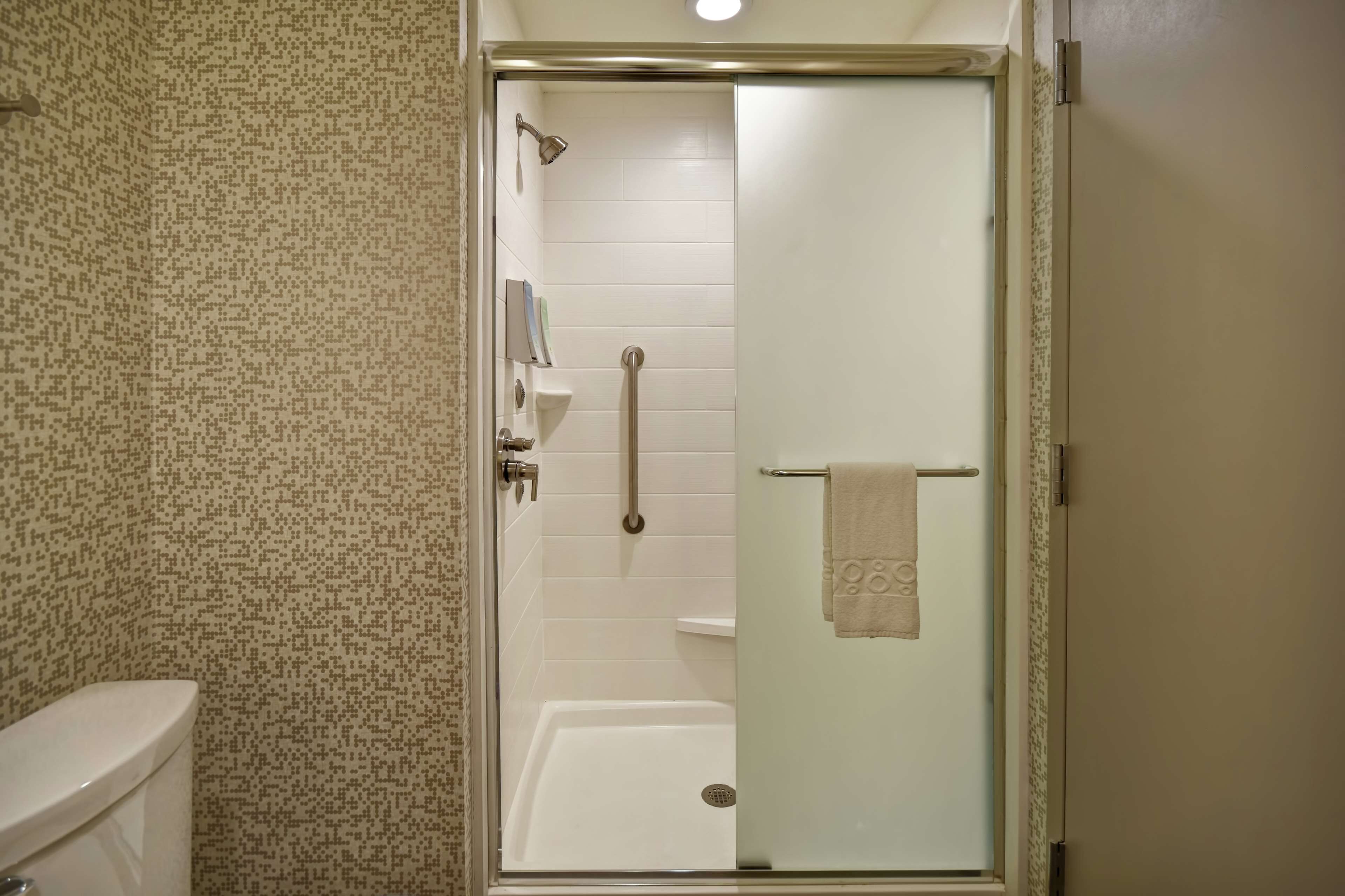 Un baño con ducha separada por vidrio, inodoro y lavamanos.