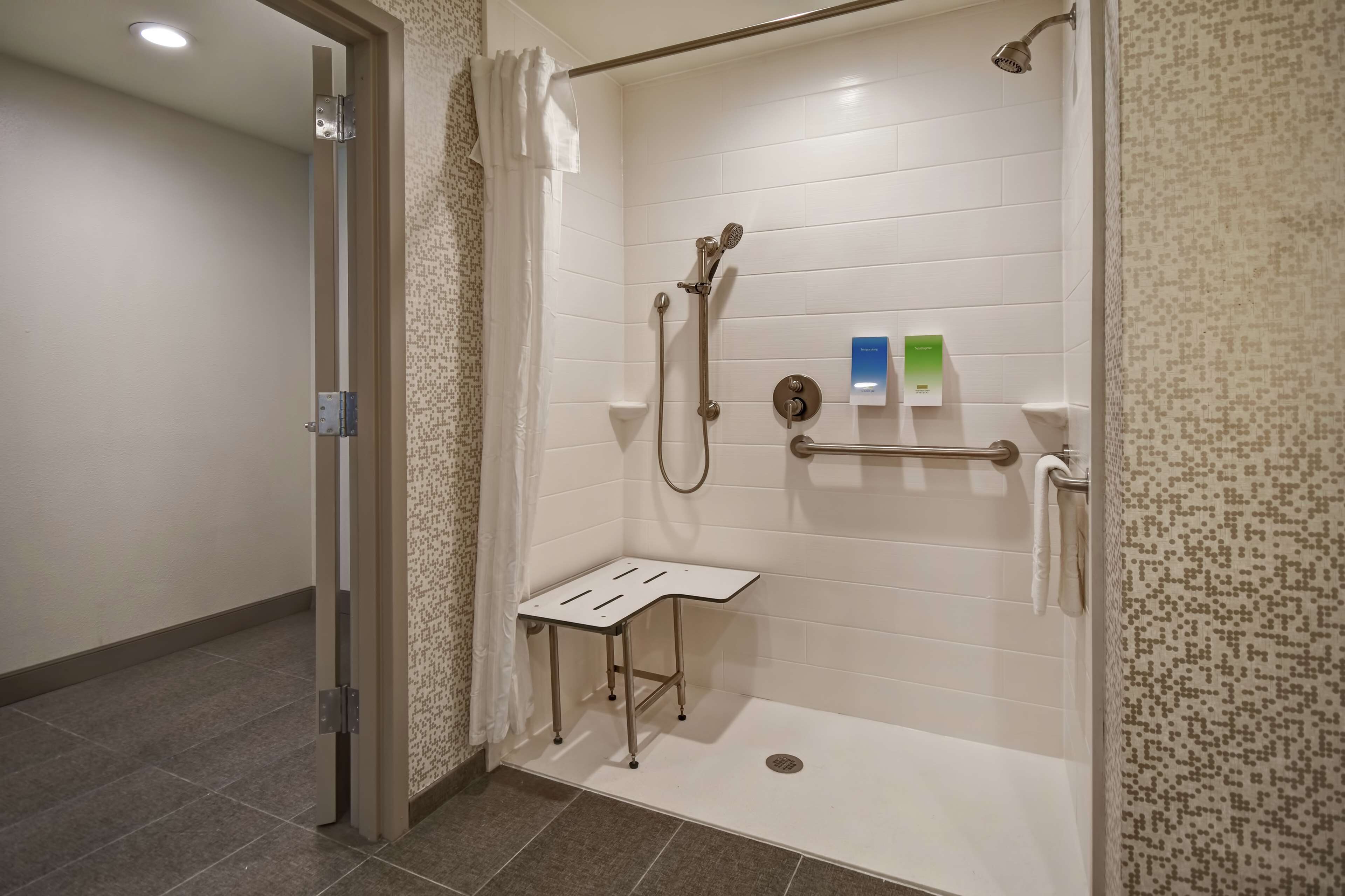 A walk-in shower with a handheld showerhead, a handheld showerhead, and a handheld showerhead.