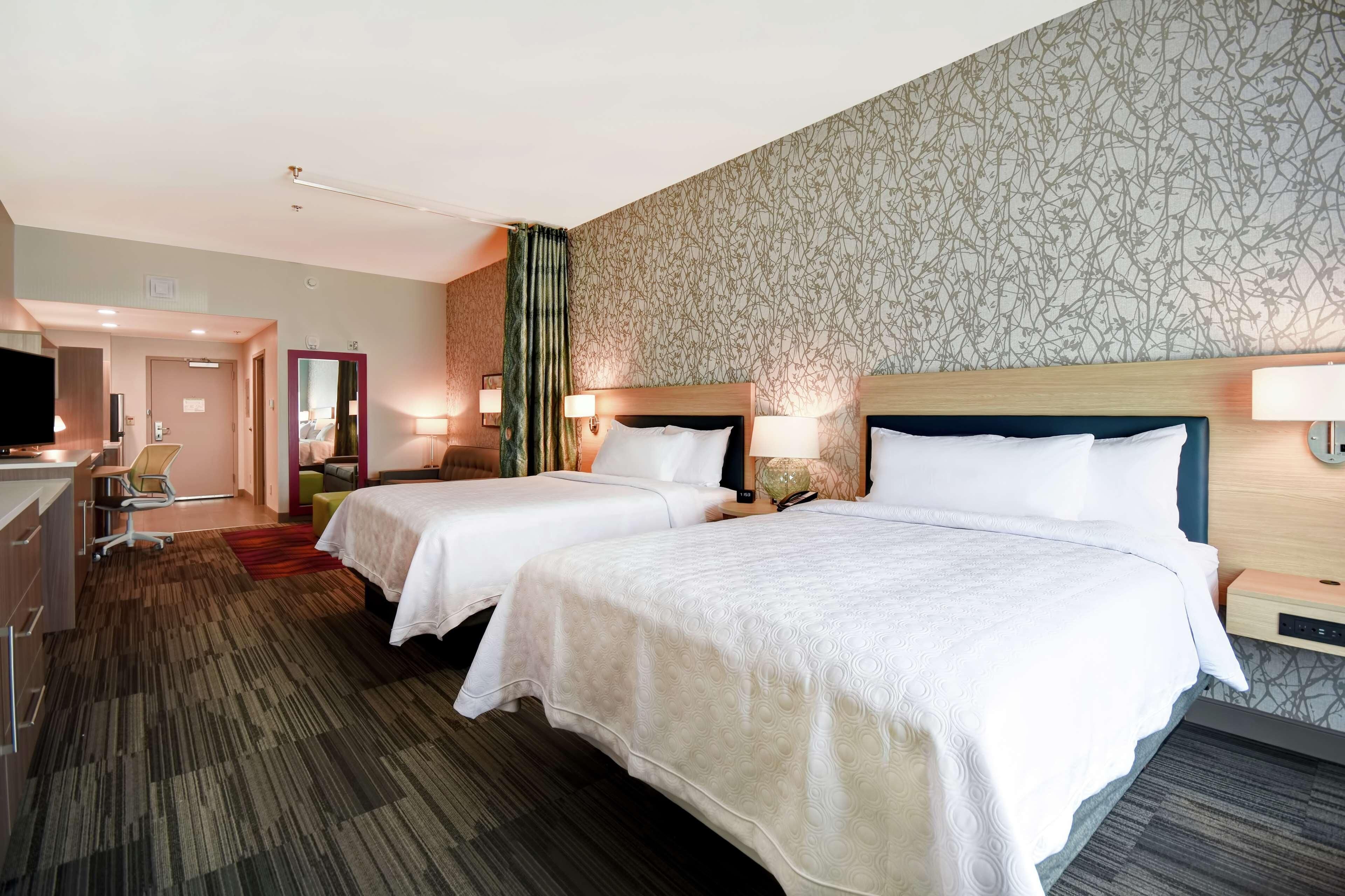 Une chambre d’hôtel avec deux lits, un bureau, une chaise, une télévision et une salle de bain.