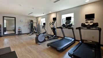 A gym with treadmills, elliptical machines, and free weights.