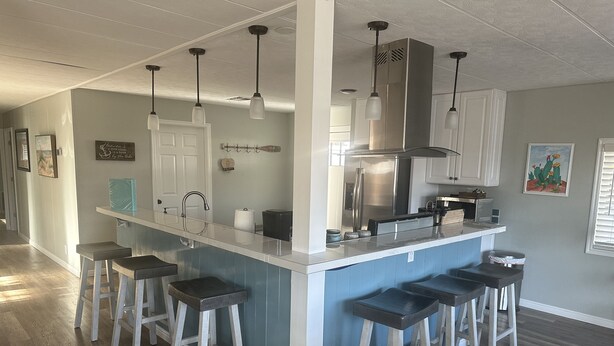 Cozinha com ilha central, banquetes, eletrodomésticos de aço inoxidável e iluminação pendente.