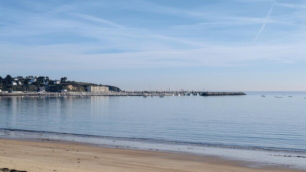 A coastal scene with a sandy beach, calm water, and a pier extending into the sea. - 3 bedroom awesome home in Matignon (Matignon)