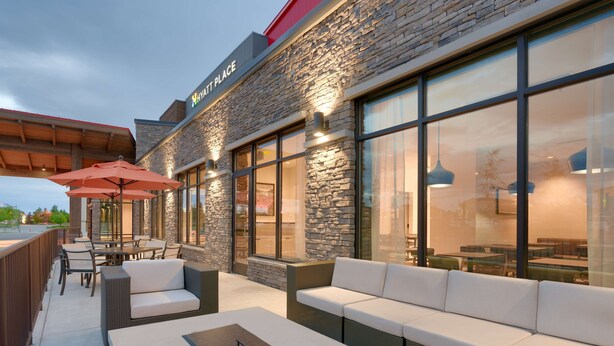 An outdoor seating area with wicker furniture and a stone facade. - Hyatt Place Anchorage Midtown (Anchorage)