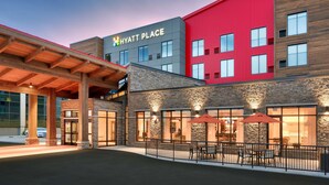 A Hyatt Place hotel with a modern design, featuring a red facade, stone accents, and outdoor seating area. - Hyatt Place Anchorage Midtown (Anchorage)