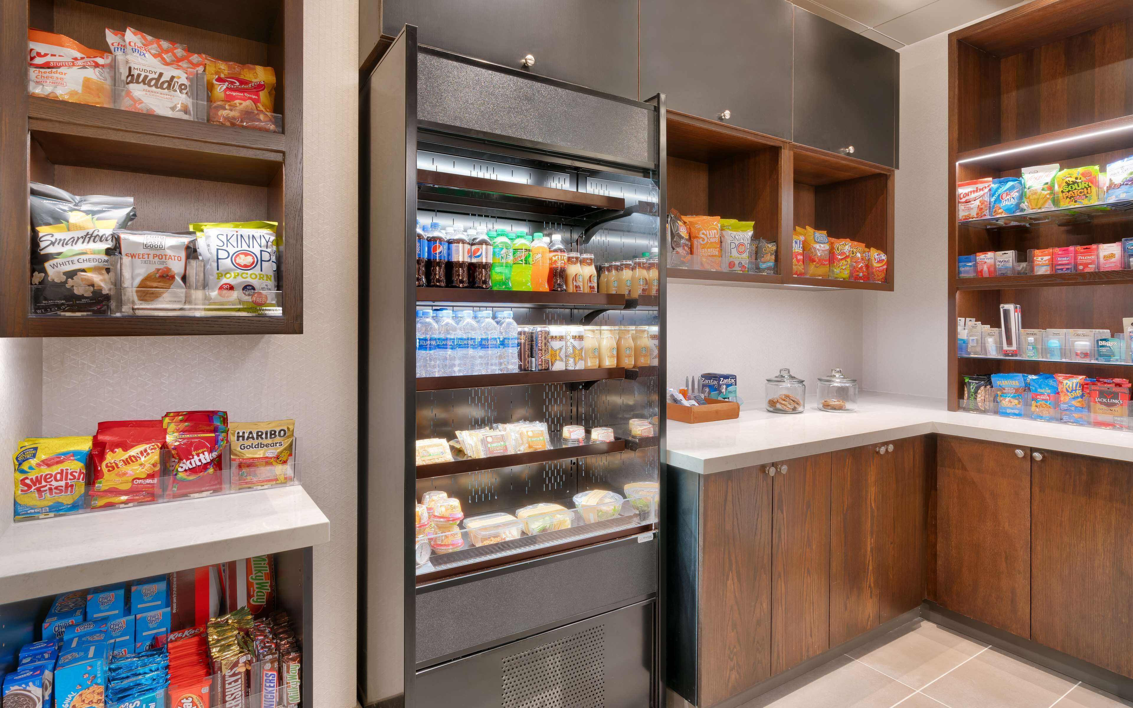 A well-stocked snack and beverage refrigerator in a hotel kitchen area.