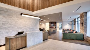 A modern lobby with a reception desk, seating area, and a stone wall. - Hyatt Place Anchorage Midtown (Anchorage)