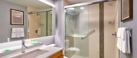 A modern bathroom with a glass-enclosed shower, a vanity with a sink, and a toilet.