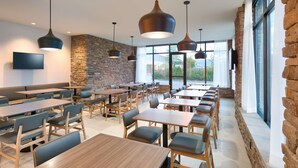 A restaurant with stone walls, large windows, and multiple seating areas. - Hyatt Place Anchorage Midtown (Anchorage)