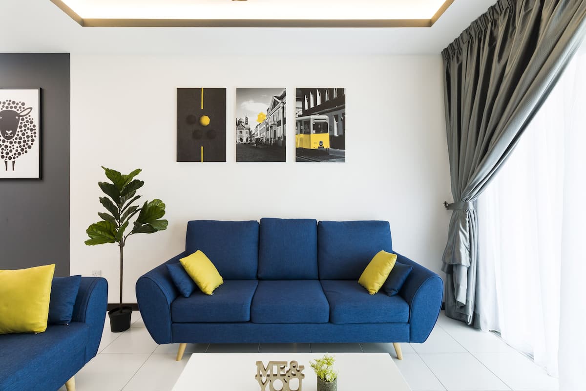 Un salon moderne avec un canapé bleu, des coussins jaunes et une plante en pot.