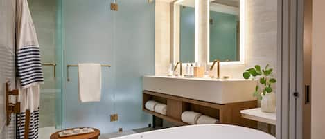 A modern bathroom with a freestanding bathtub, a glass shower enclosure, and a vanity with a mirror.