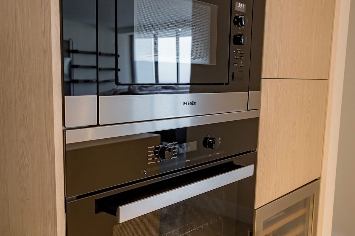 A kitchen with a built-in microwave, oven, and a microwave above the oven.