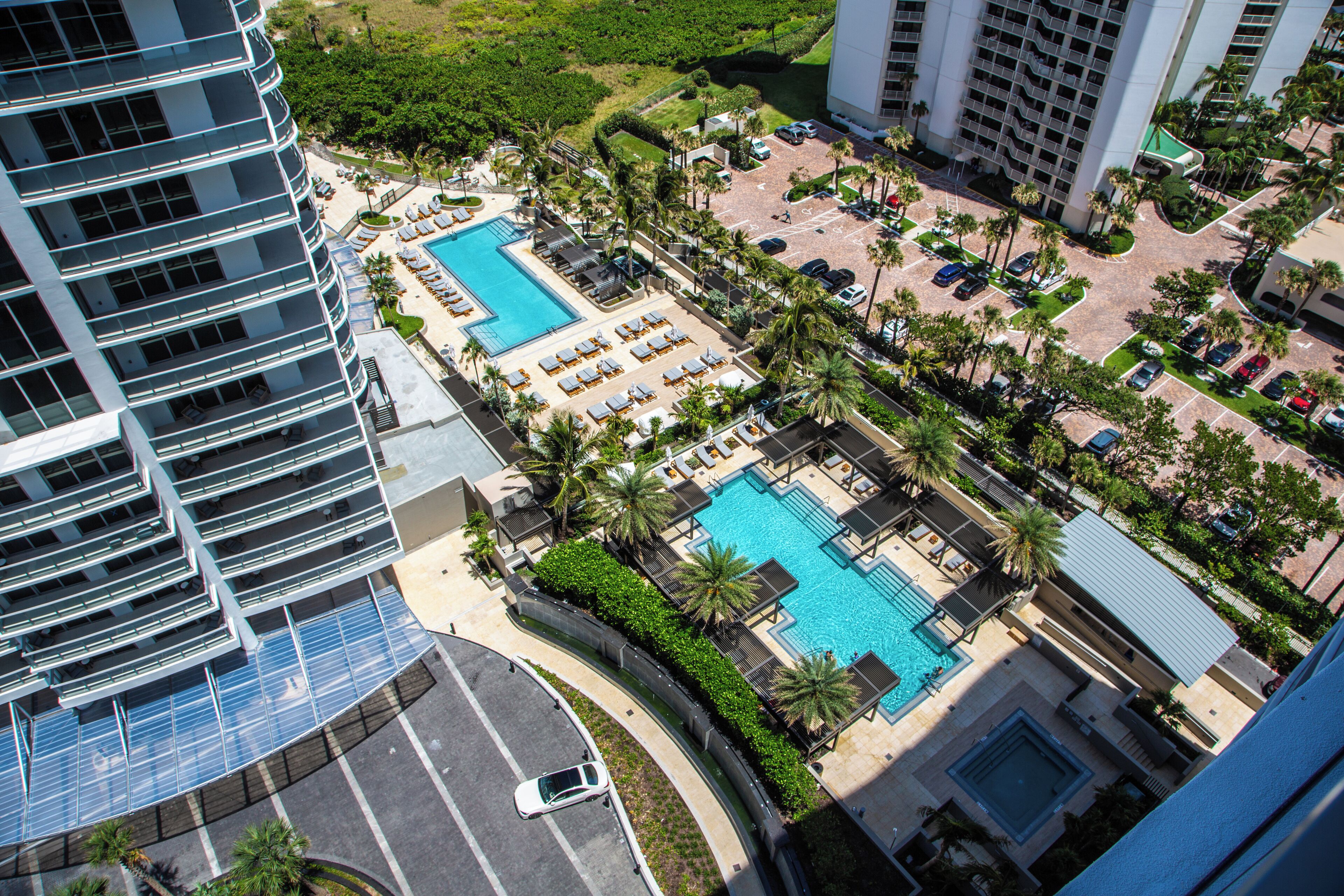 A high-rise hotel with a rooftop pool, multiple balconies, and a landscaped garden area.
