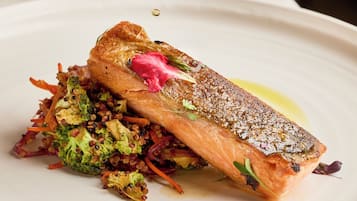 Un plato de comida con salmón, brócoli y zanahorias.