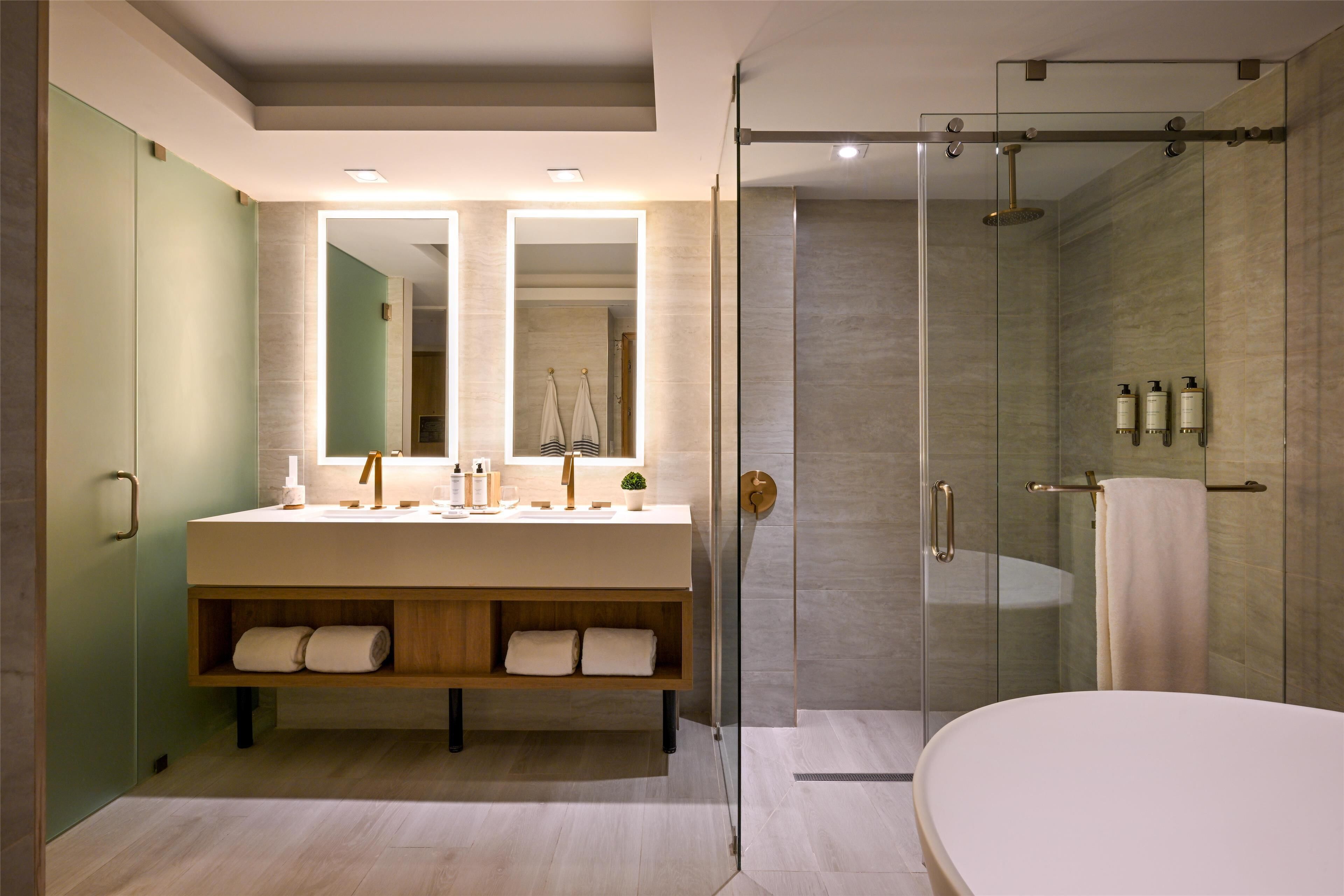 A modern bathroom with a large mirror, a freestanding bathtub, and a glass-enclosed shower.