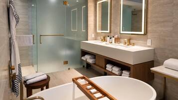 A modern bathroom with a freestanding bathtub, a glass-enclosed shower, and a vanity with dual mirrors.